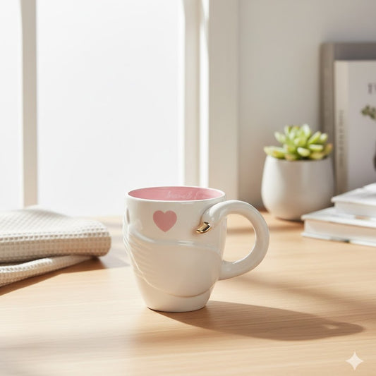 White mug with pink interior and heart design on a wooden surface with a soft focus background