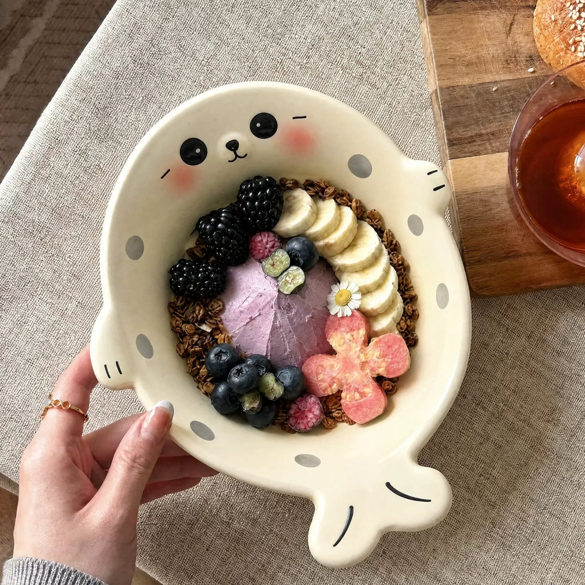 White seal-shaped bowl filled with fruit and granola