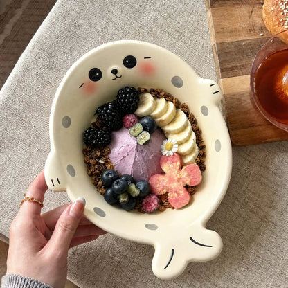 White seal-shaped bowl filled with fruit and granola