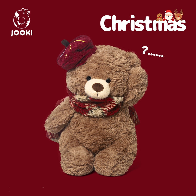 Teddy bear wearing a red hat and scarf on a red background with Christmas text.