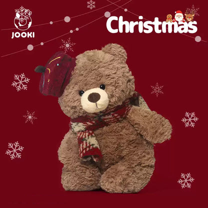 Teddy bear wearing a Christmas hat and scarf on a red background with snowflakes, featuring the JOOKI brand.