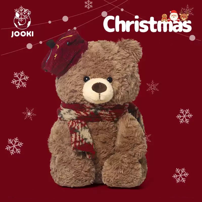 Brown teddy bear wearing a red hat and scarf on a red background with Christmas text and snowflakes.