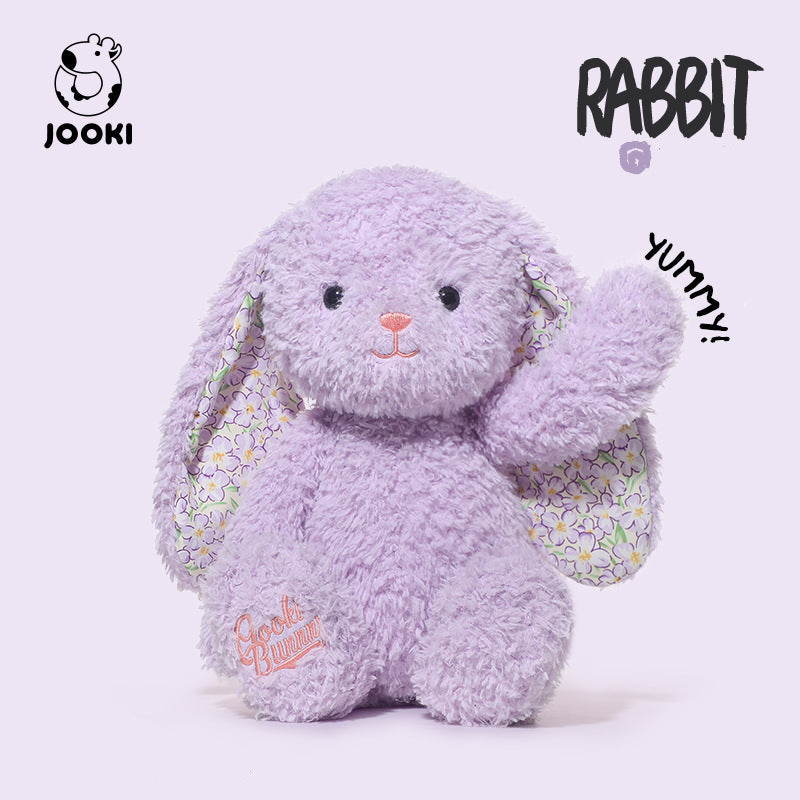 Purple plush rabbit toy with a floral bag on a white background, featuring the brand 'Jooki'.