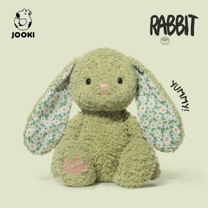 Green plush rabbit toy with floral ears on a beige background, featuring the brand 'Jooki'.