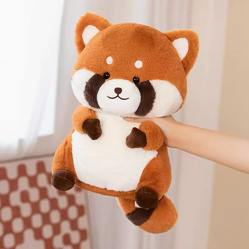 Plush toy red panda held by a hand against a neutral background