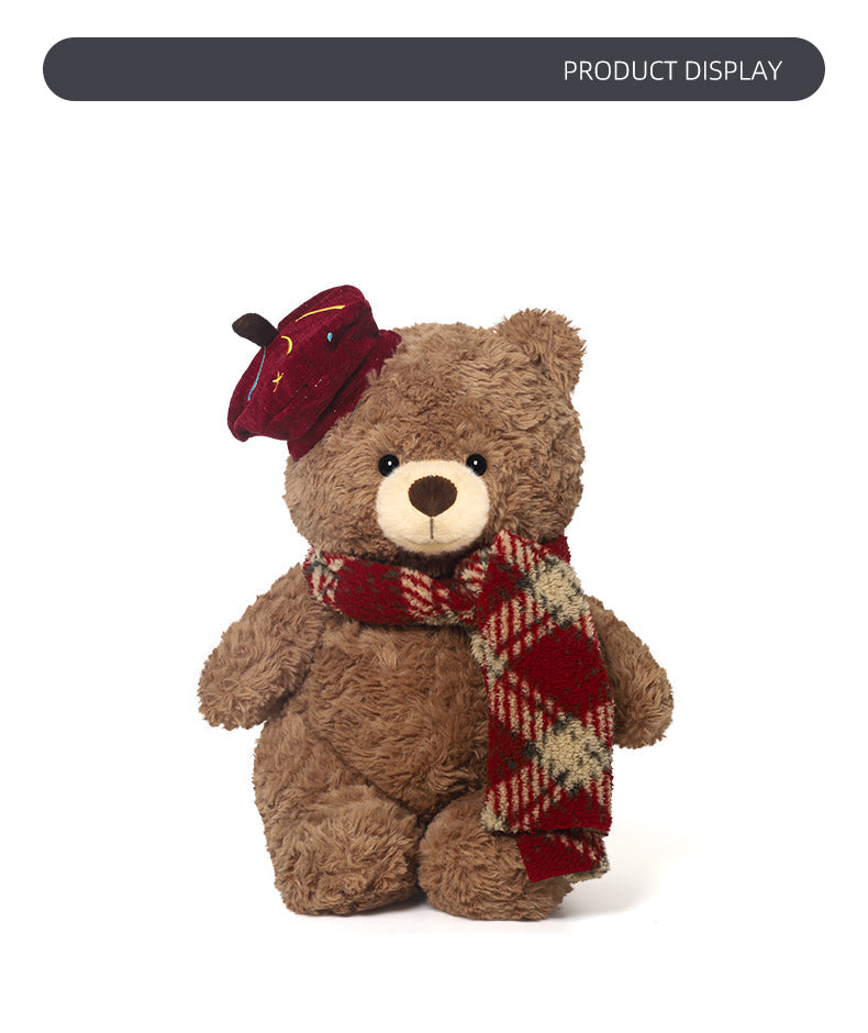 Plush teddy bear wearing a red hat and scarf on a white background