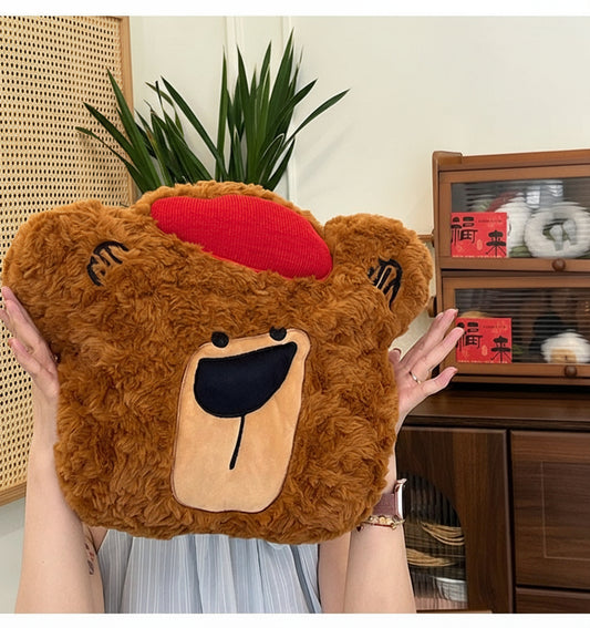 A plush bear toy with a red nose in a room with a plant and wooden cabinet.