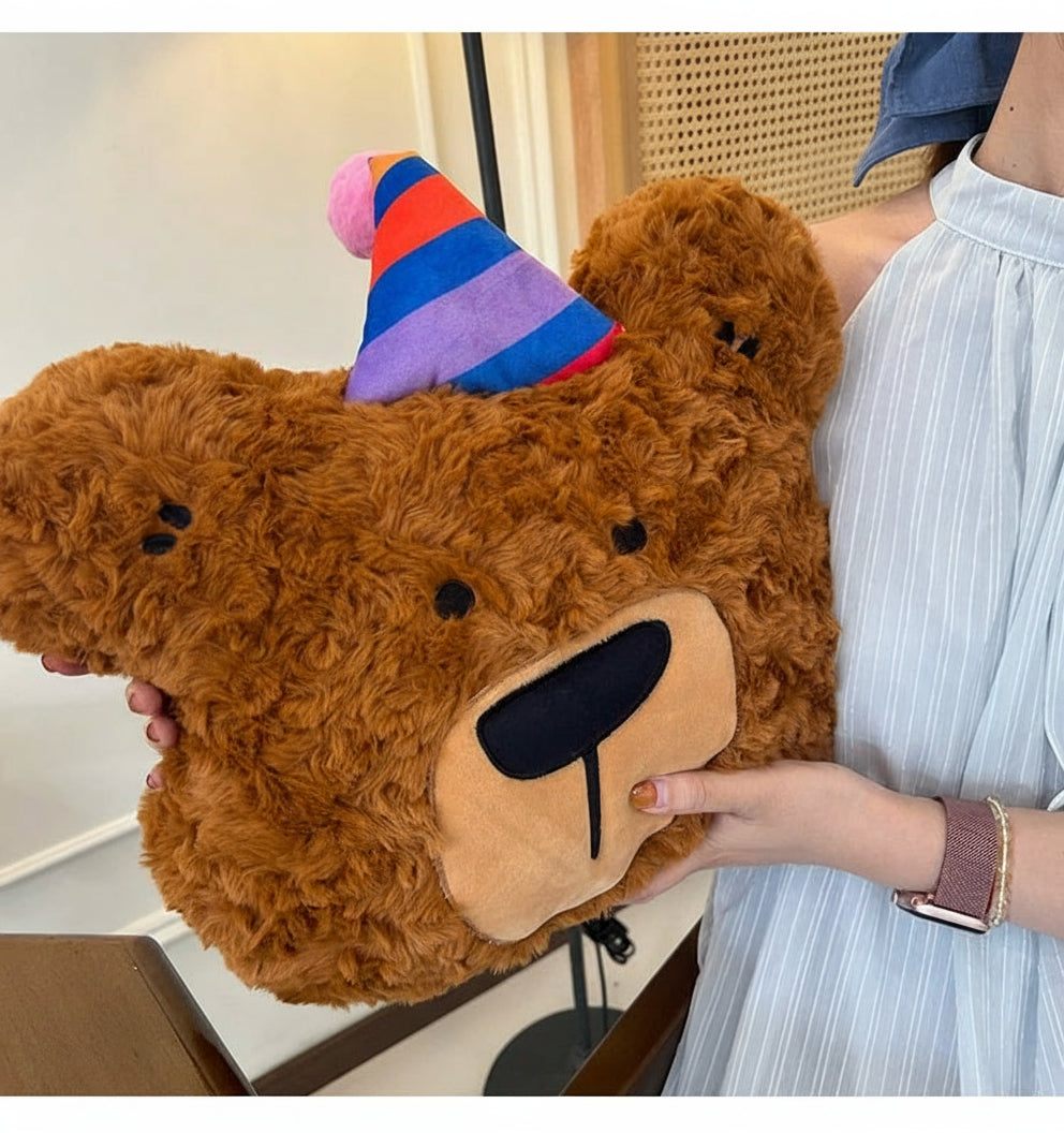 Person holding a large brown teddy bear with a colorful striped hat indoors.