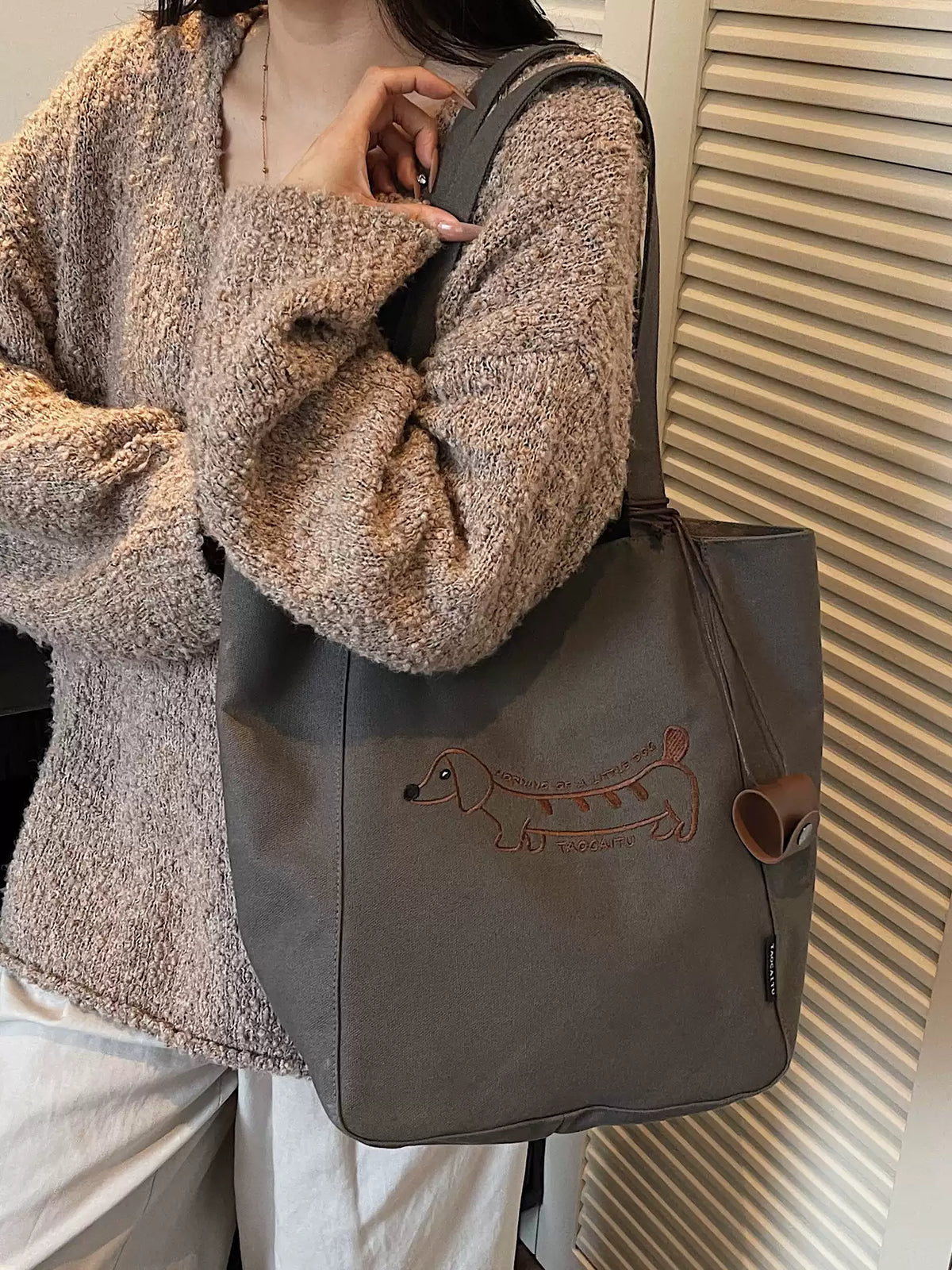 Black embroidered dachshund tote bag worn over the shoulder