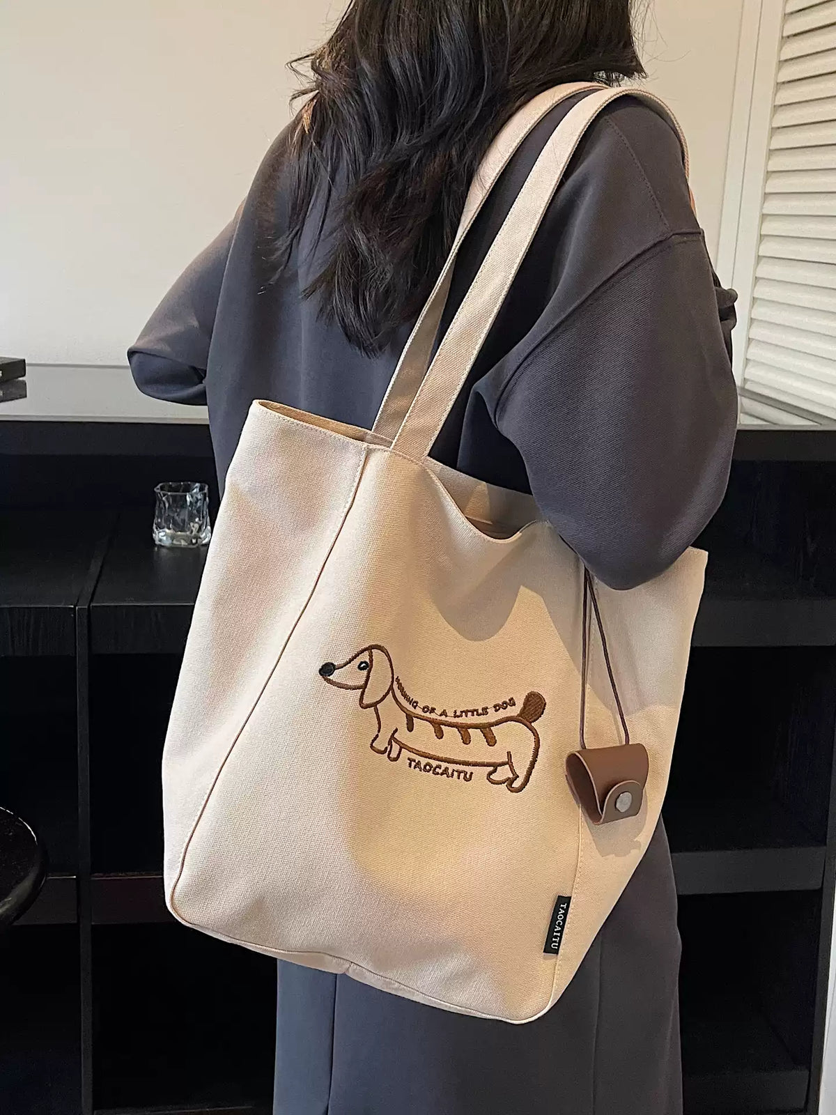 Khaki embroidered dachshund tote bag worn over the shoulder